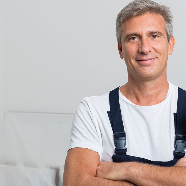 Freundlich lächelnder Handwerker vor weisser Wand